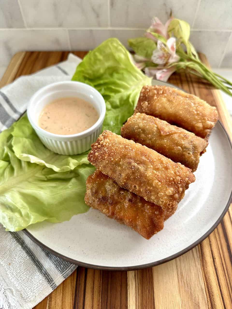 Egg rolls on a plate served with a dipping sauce