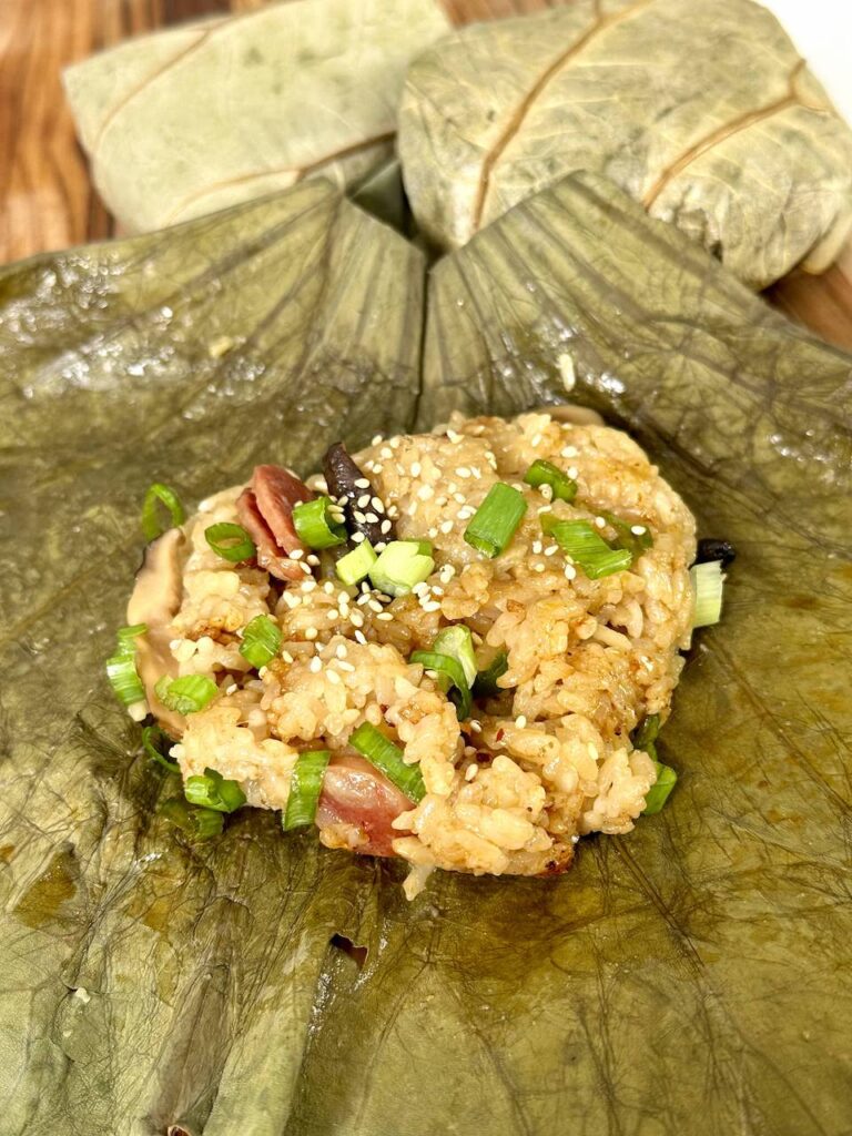 Sticky rice in an unwrapped lotus leaf with green onions and scallions on top