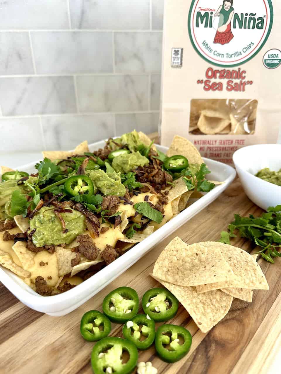 Plate of tortilla chips topped with truffle cheese, beef, guacamole, and jalapeno