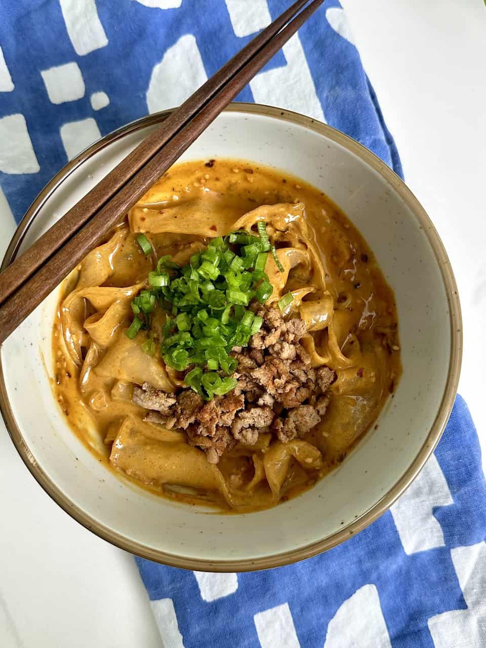 Spicy Szechuan rice paper noodles in a bowl with chopsticks