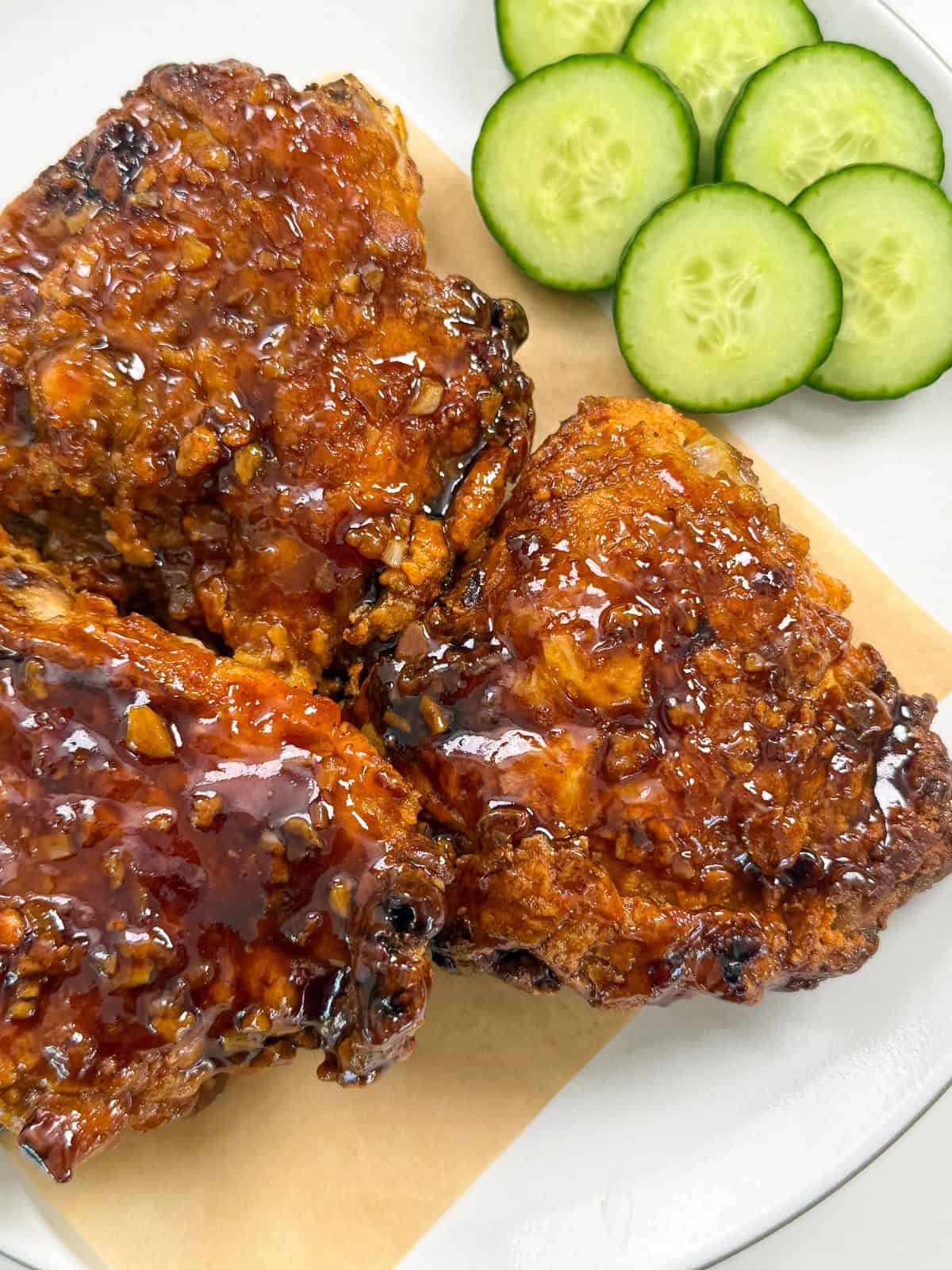 Honey butter fried chicken on a plate with cucumbers side view