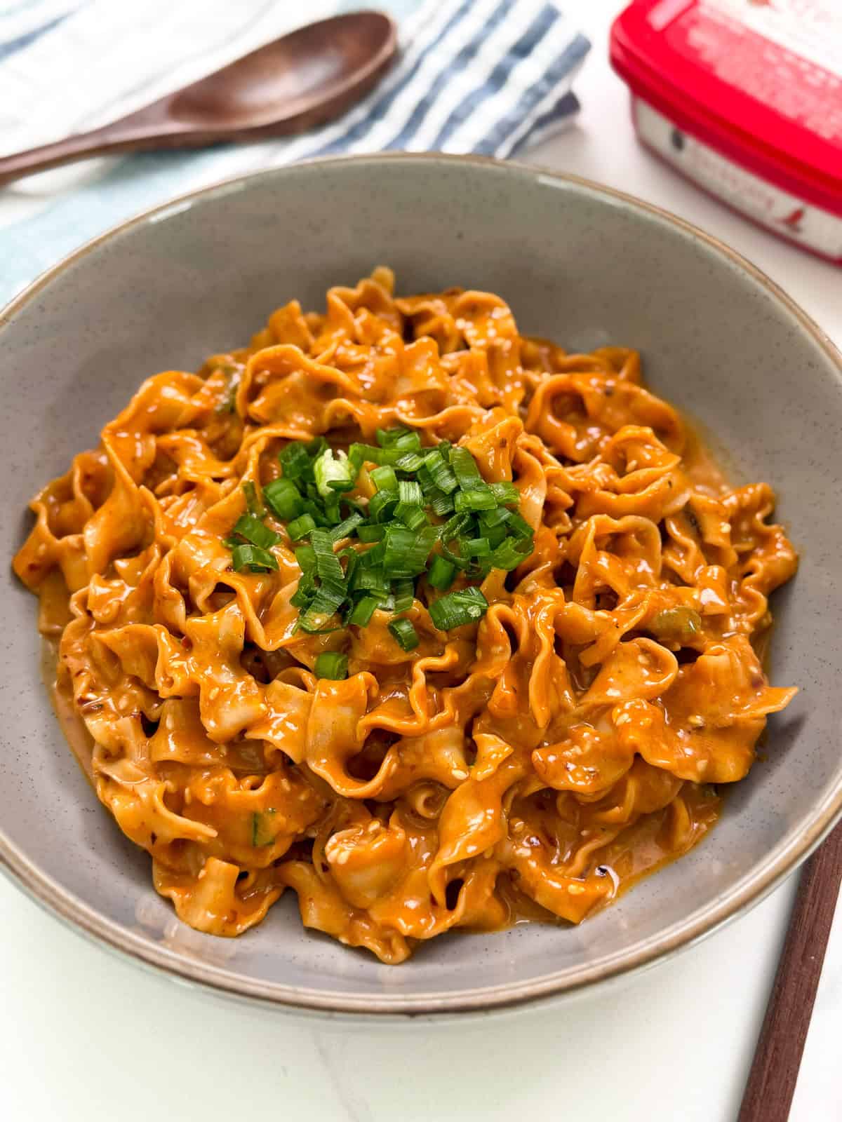 Peanut Gochujang Chili Noodles with chopsticks and green onions side view