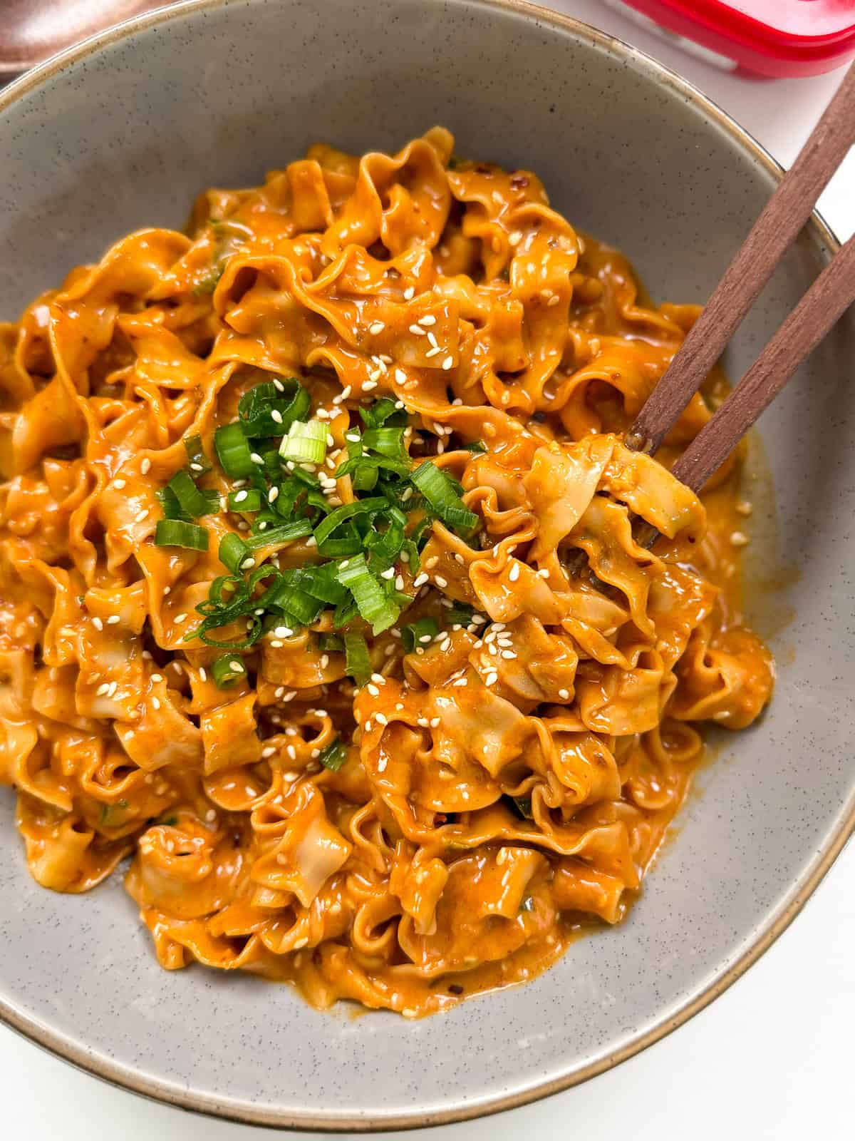 Peanut Gochujang Chili Noodles with chopsticks and green onions offset view