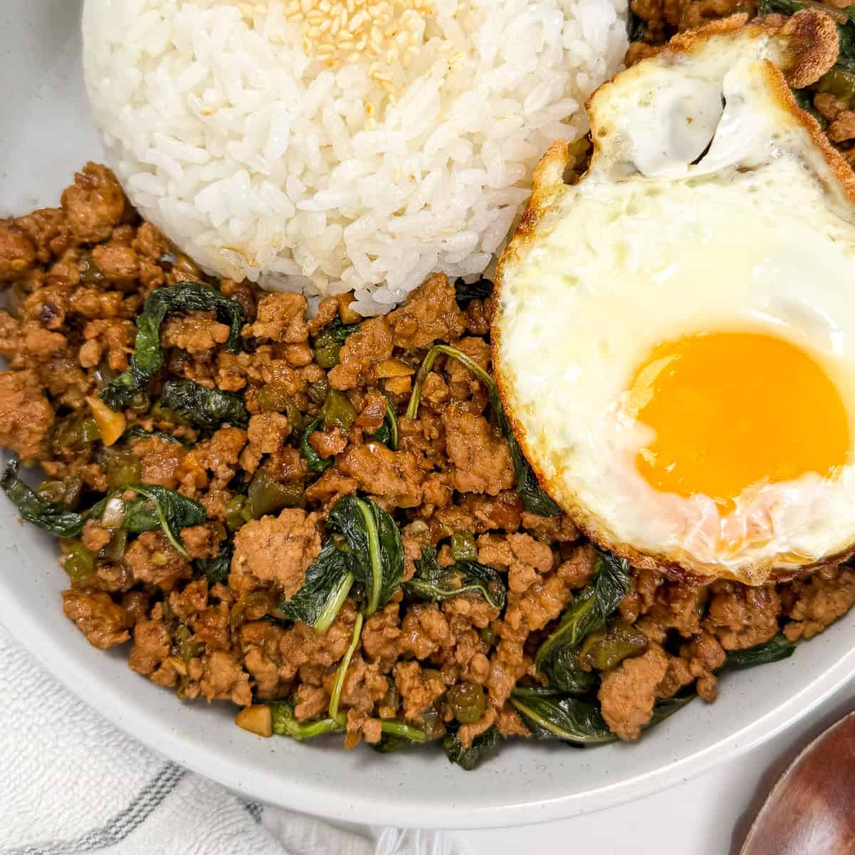 Pad Kra Pao (Ground Pork & Holy Basil Stir-Fry) in a bowl with white rice and fried egg featured view