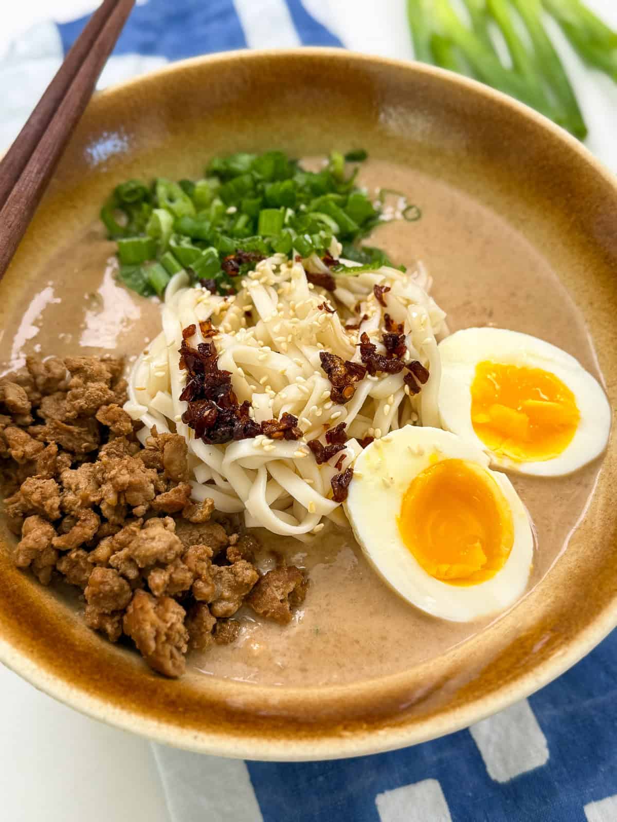 Creamy Peanut Miso Ramen with ground pork, eggs, and green onion side view