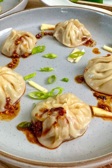 Pork Soup Dumplings on a plate with chili sauce featured view