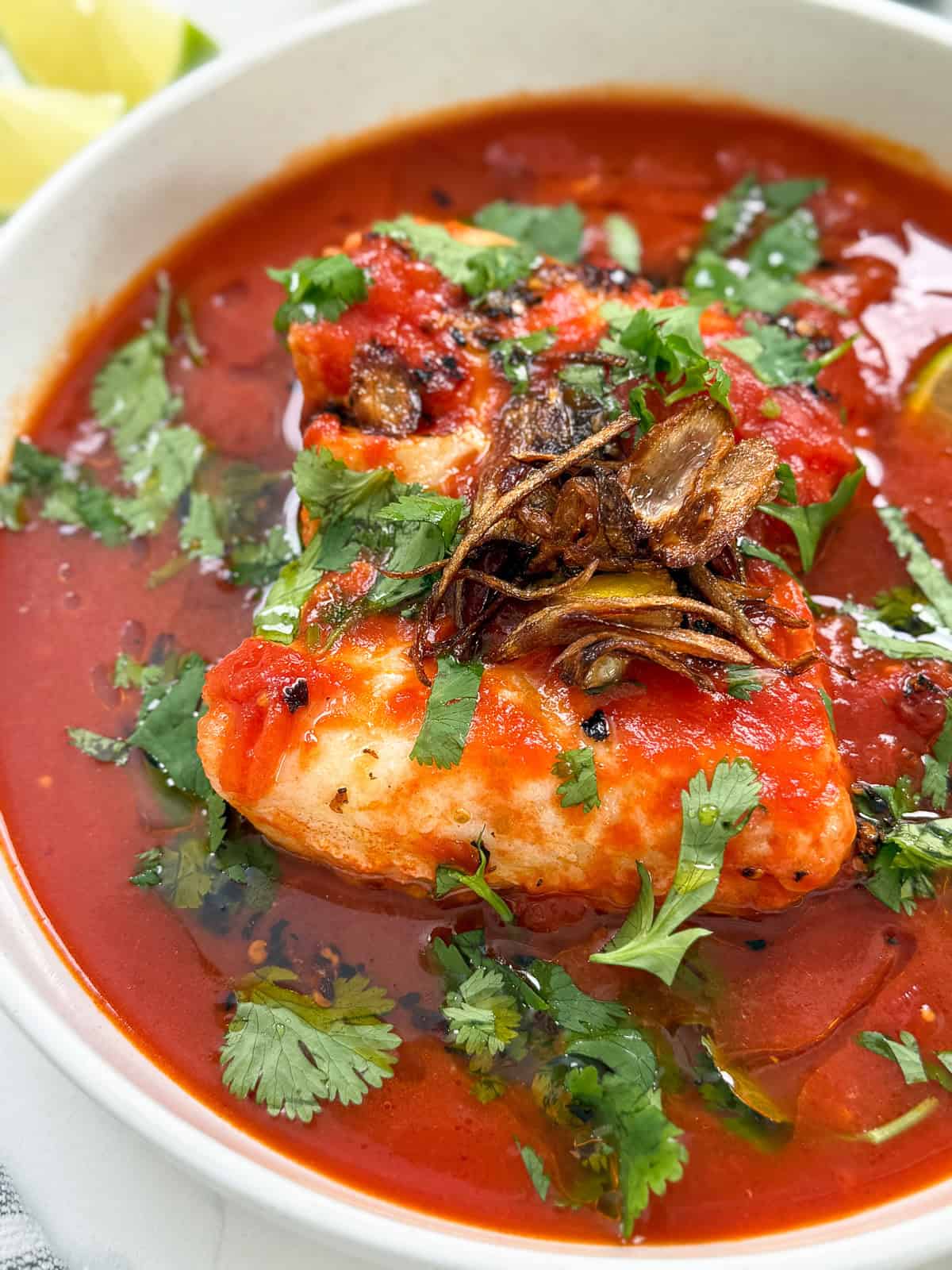 Tomato Poached Fish with Shallot Oil in a bowl side view