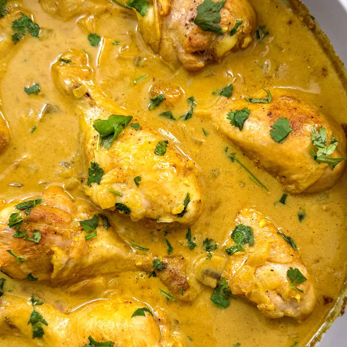 Coconut curry chicken in a large pan featured view