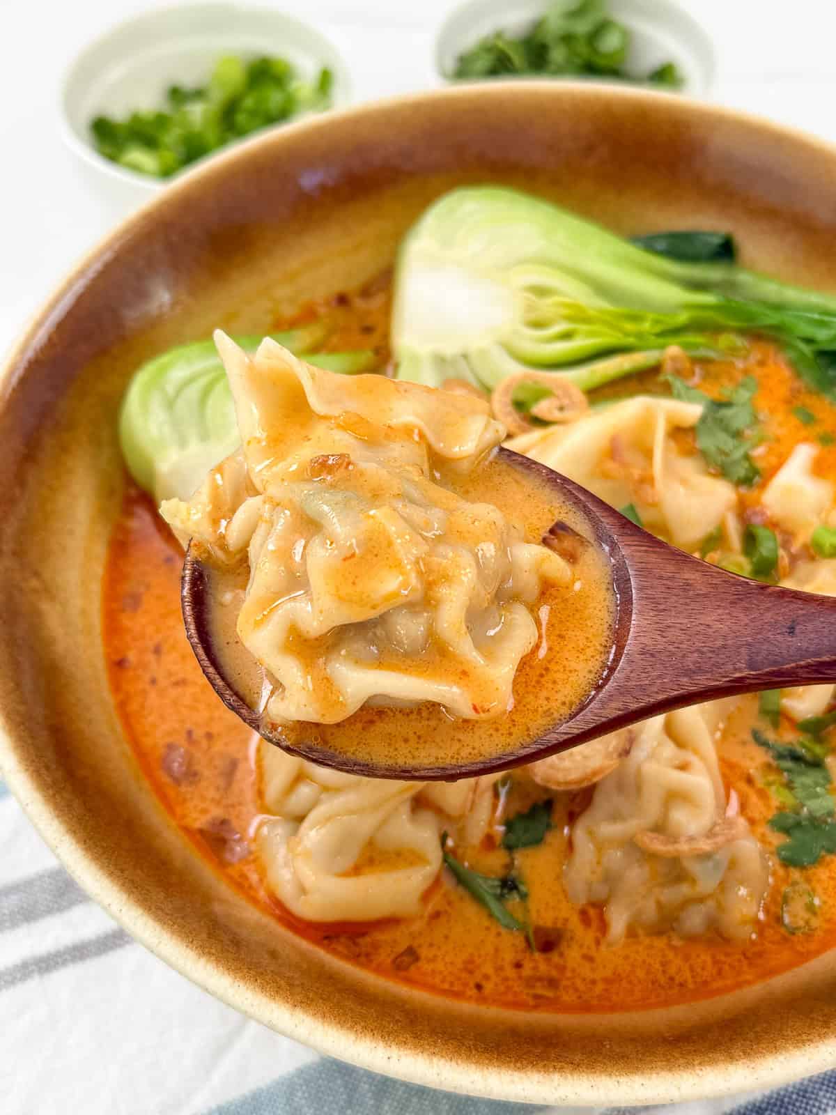 Thai Red Curry Wonton Soup in a bowl with soup lifting wonton