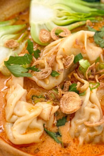 Thai Red Curry Wonton soup in a bowl with bok choy and fried shallots