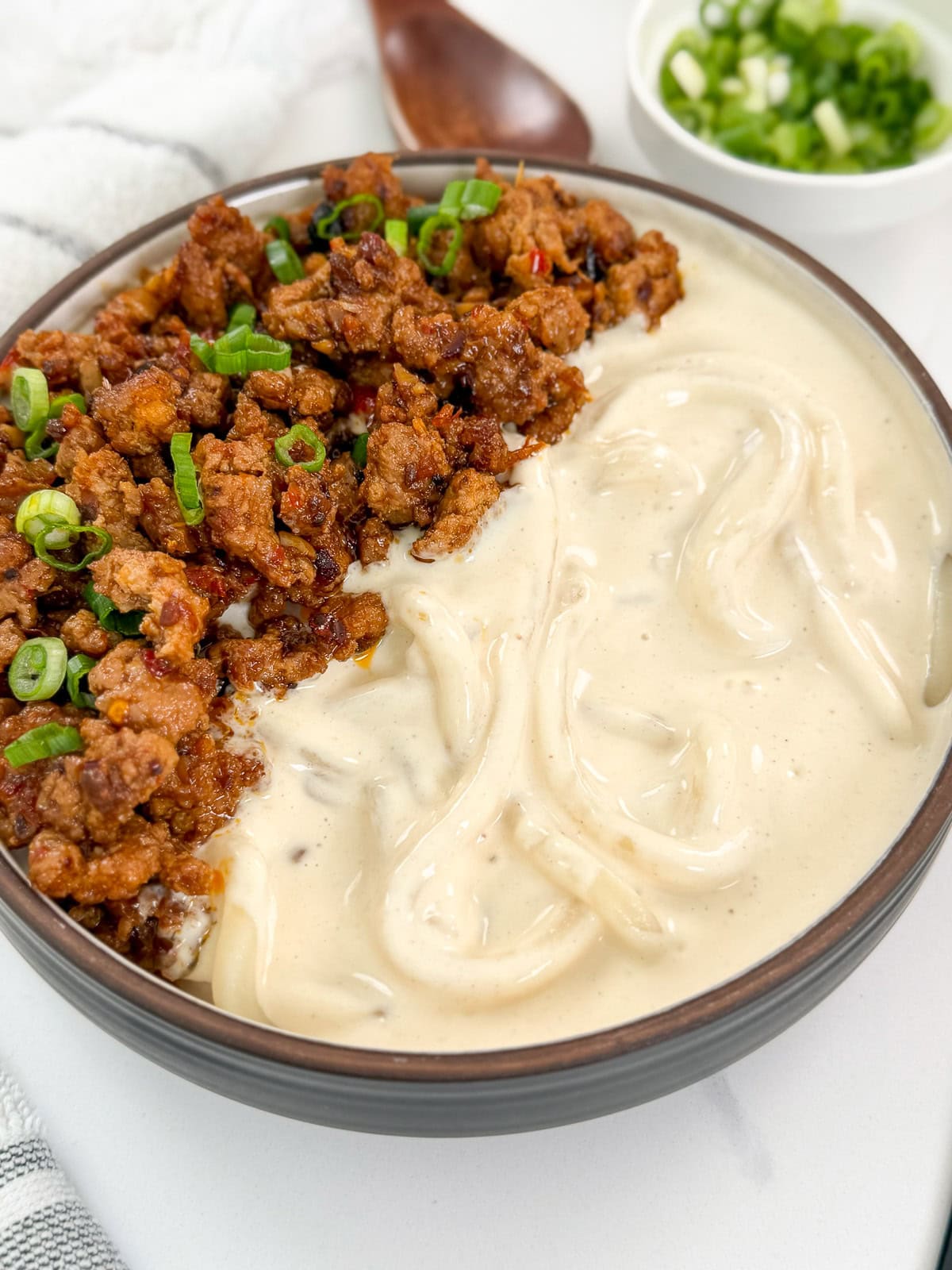 Creamy Mapo Tofu Udon in a bowl with marinated minced meat and green onions on top