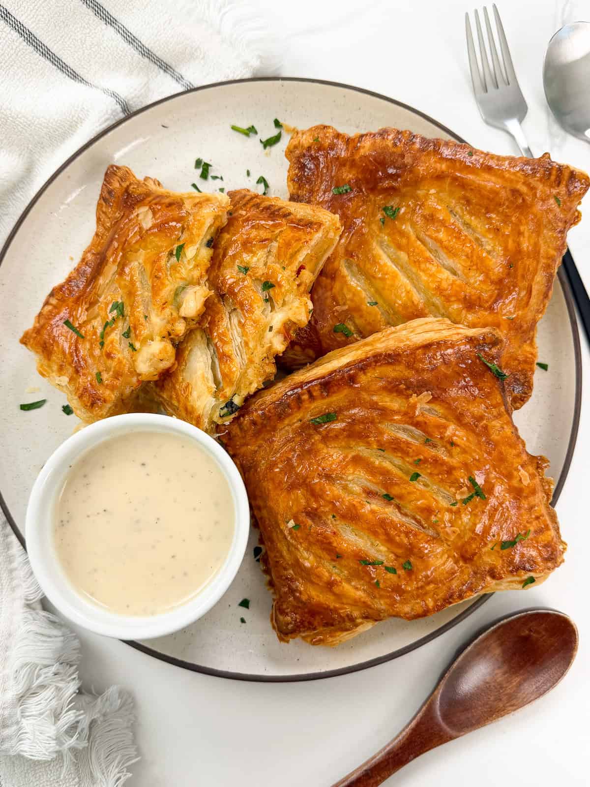 Marry Me Chicken Hot Pockets on a large plate with ranch dipping sauce on the side. There is a spoon and a towel next to the plate.