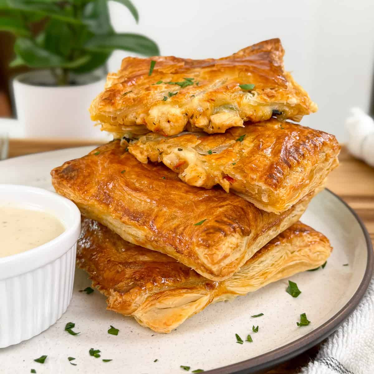 Marry Me Chicken Hot Pockets on a round plate with ranch dipping sauce on the side and chopped parsley on top