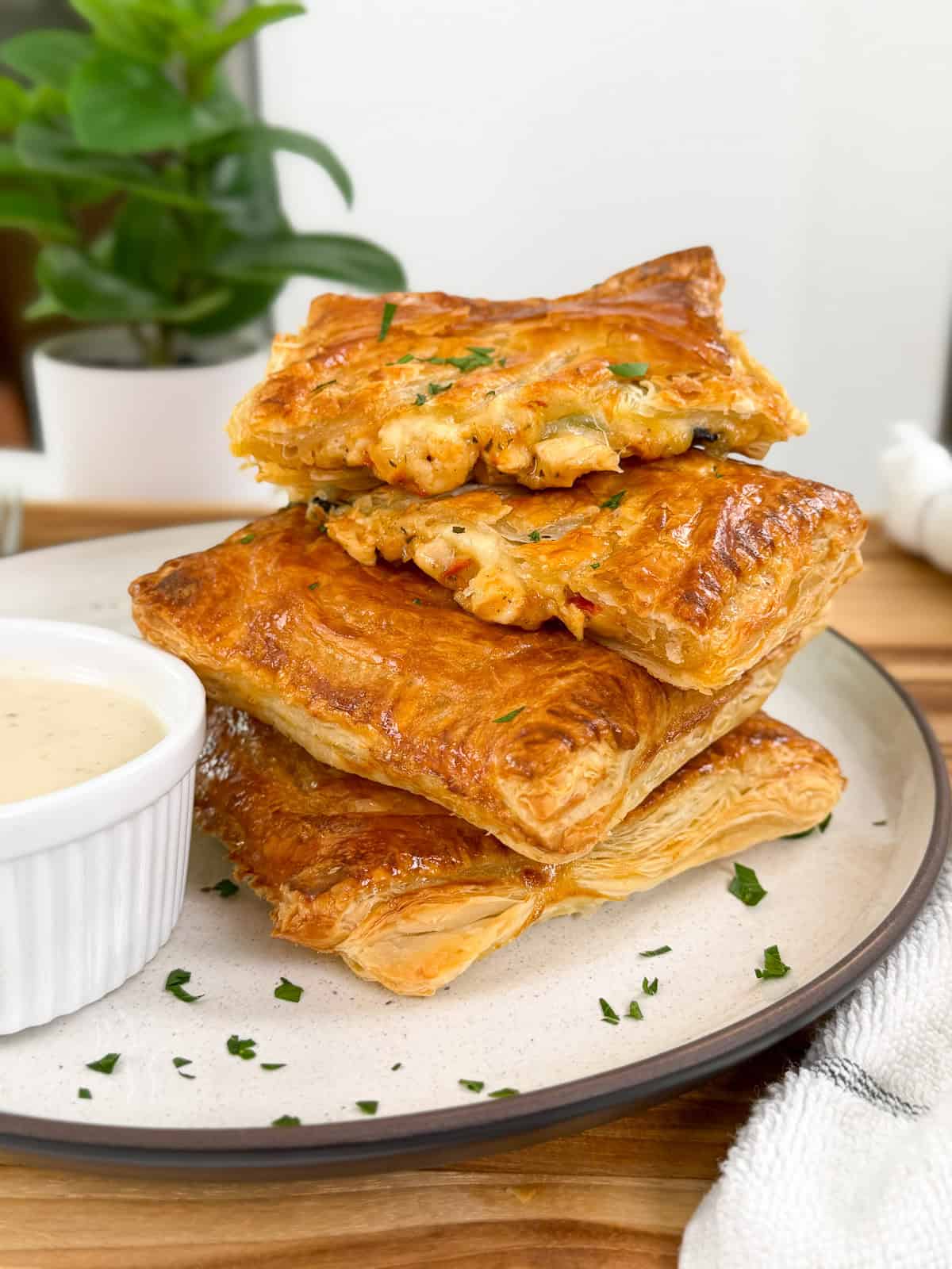 Marry Me Chicken Hot Pockets stacked on a large plate with ranch sauce on the side and chopped parsley on top