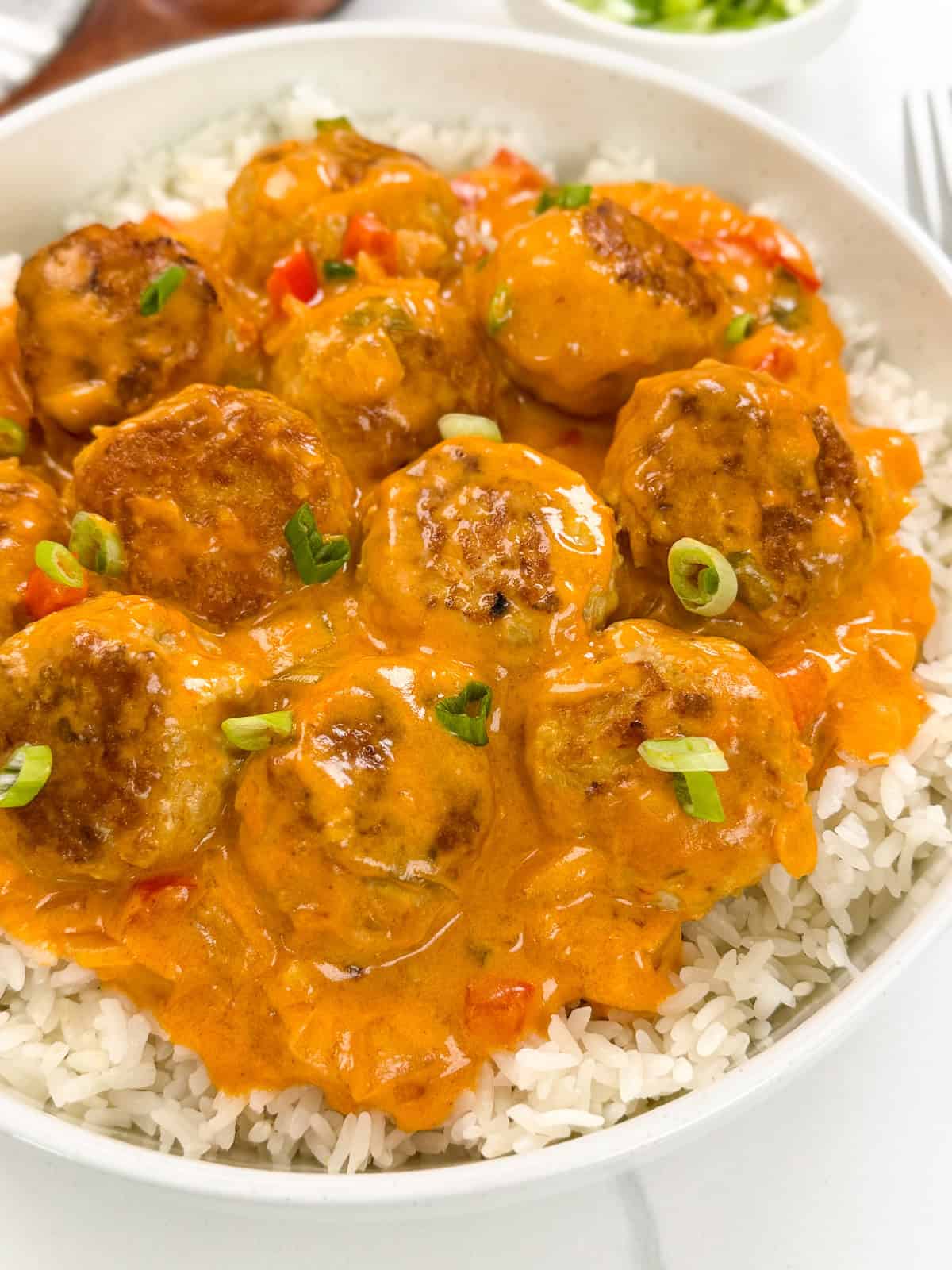 Thai Turkey Meatballs in a Coconut Curry Sauce sitting on top of a bed of white rice with green onions on top. This is a more zoomed in view.